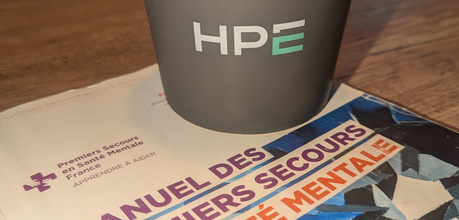 Manuel Premiers Secours en Santé Mentale et mug Hewlett Packard Enterprise lors d'une formation PSSM à Grenoble.