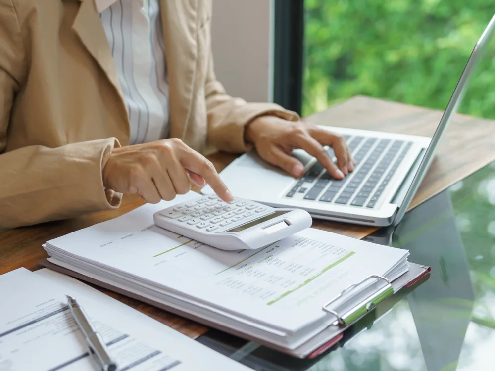Une personne utilise une calculatrice devant un ordinateur