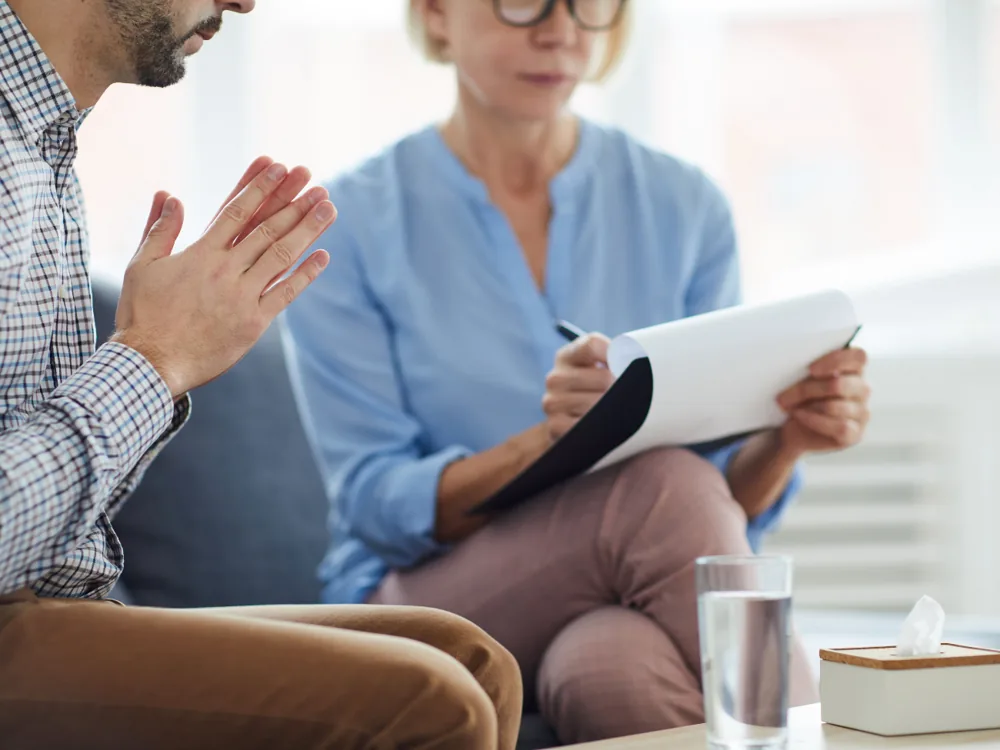 Échange entre un homme et une professionnelle prenant des notes